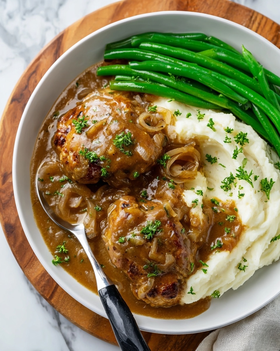 The dish shows a white plate filled with three main parts. On the left, three browned cooked pieces covered in thick brown gravy with visible bits of cooked onion and sprinkled with small green parsley leaves. On the right side, there is a creamy white mashed layer with smooth texture topped with more brown onion gravy. At the top, bright green cooked green beans are arranged in a neat row. A spoon with a black and silver handle is placed resting on the plate’s edge, touching the mashed layer. The plate is on a round wooden board with a white marbled surface underneath. Photo taken with an iphone --ar 4:5 --v 7