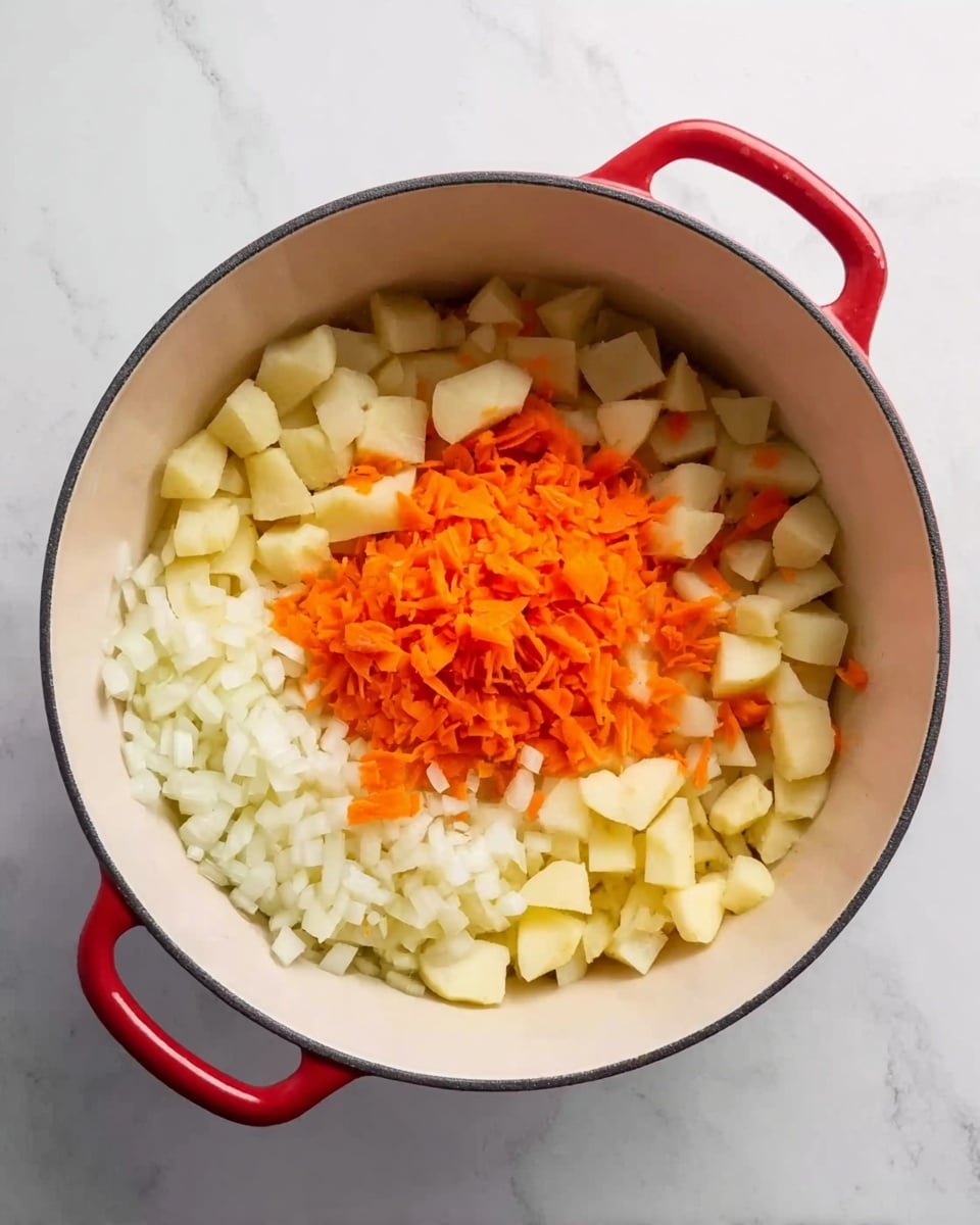 A white deep round pot with two red handles sits on a white marbled surface. Inside the pot, there are three layers of chopped vegetables: the bottom layer is diced white onions spread evenly, on top of that is a thick layer of small diced white potatoes covering about half the pot, and in the center on top of the onions is a smaller pile of grated bright orange carrots. The pot’s smooth interior contrasts with the colorful vegetables inside. photo taken with an iphone --ar 4:5 --v 7