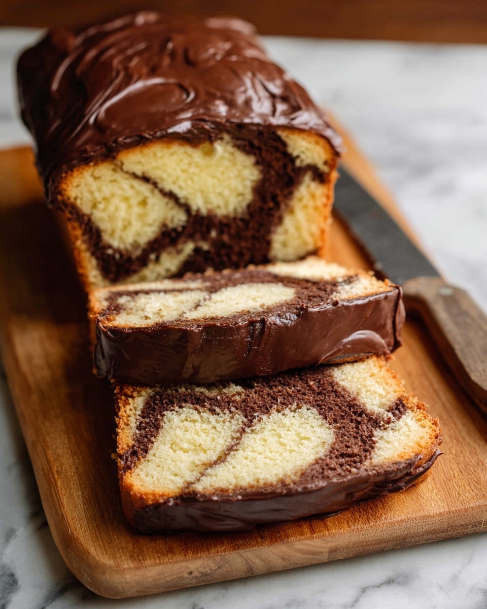 A loaf of marble cake sits on a wooden board, sliced to show two thick pieces in front and the rest of the loaf behind. The cake has a light yellow base color with dark brown swirl patterns running inside. The entire top and sides of the loaf are covered in a thick, smooth layer of shiny dark brown chocolate frosting. The wooden board contrasts with the white marbled surface underneath it. A large knife lies next to the cake loaf. photo taken with an iphone --ar 4:5 --v 7
