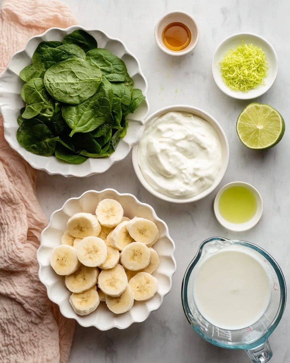 The image shows several small white bowls arranged on a white marbled surface, each containing a different ingredient. In the center, there is a white bowl filled with even slices of banana, pale yellow with soft texture. To the bottom left, green, fresh spinach leaves fill a white scalloped bowl, creating a deep green leafy layer. Above the spinach, a bowl holds thick white creamy yogurt with a smooth surface. To the top right of the banana, finely grated bright lime zest sits on a small white plate, while next to it are two half limes showing their green flesh. To the right, a clear measuring cup is filled with white liquid, likely coconut milk. Below it, a small white bowl contains a light greenish-yellow liquid, possibly oil or juice. At the top center, a tiny bowl holds a small amount of brownish syrup or honey. A light peach cloth is placed softly on the left edge of the frame. Photo taken with an iphone --ar 4:5 --v 7
