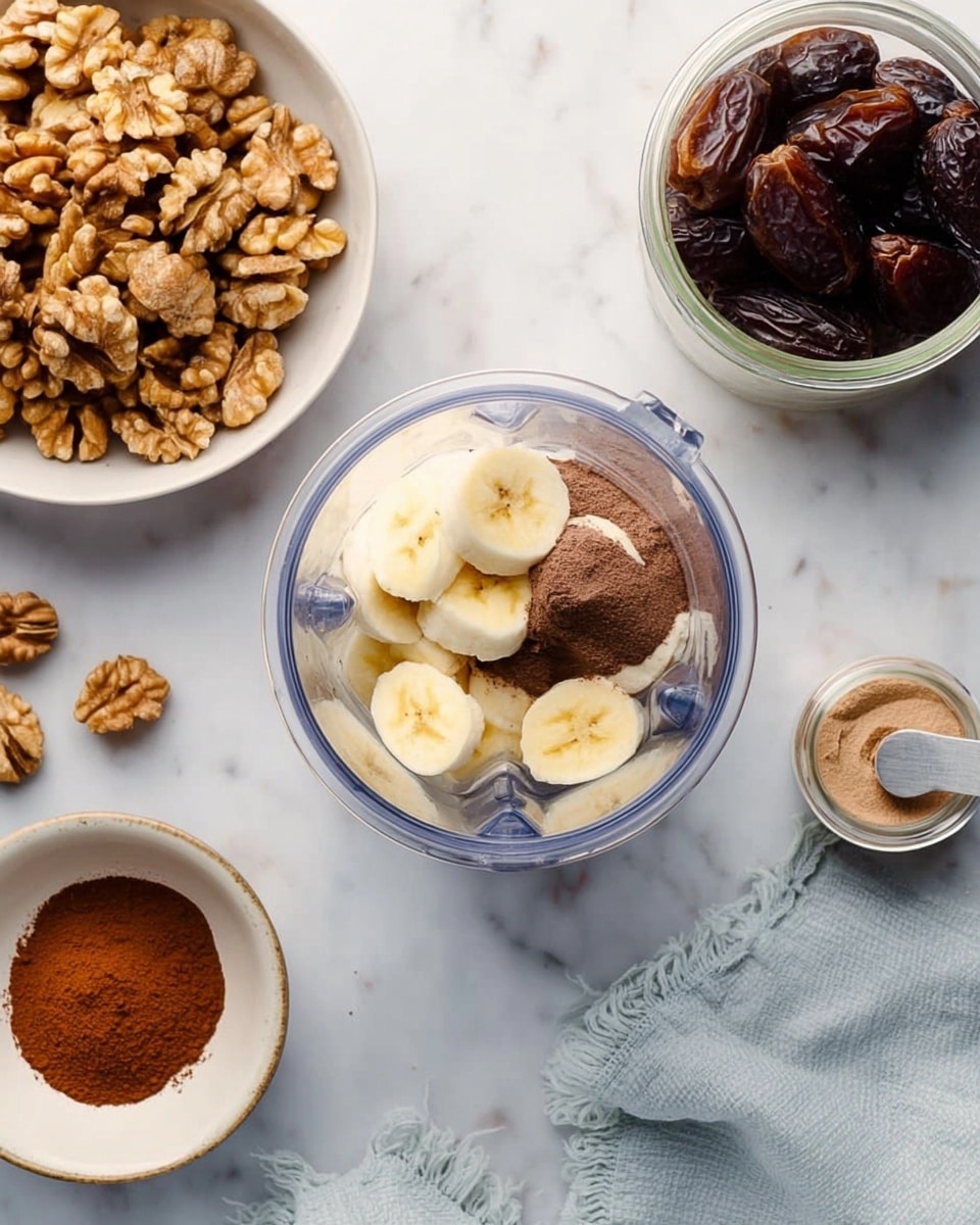 The image shows a clear blender cup in the middle with two layers inside: the bottom layer is a dark brown paste-like texture and on top are sliced yellow banana pieces. To the left of the blender, there is a white bowl filled with whole brown walnuts, and below it, a small white bowl containing a heap of brown powder with a small round scoop. To the right of the blender, there is a glass jar filled with dark brown dates and a light gray cloth near the jar. The surface is a white marbled texture. photo taken with an iphone --ar 4:5 --v 7