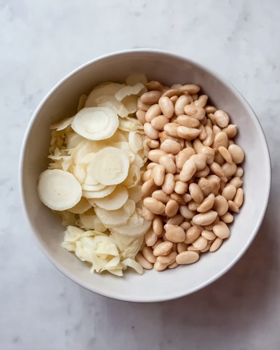 A white bowl sits on a white marbled surface, filled with two main ingredients placed side by side. On the left half, there are small, thin white slices of a round vegetable or root with a smooth texture. On the right half, there is a pile of pale brown, oval beans with a shiny appearance. The two ingredients contrast well in color and texture, creating a simple and clean look. photo taken with an iphone --ar 4:5 --v 7