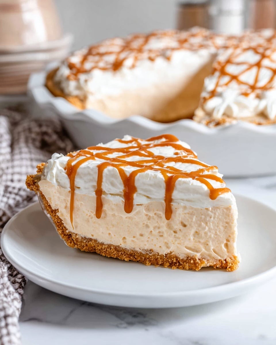 The image shows a slice of pie on a white plate with three distinct layers. The bottom layer is a thin golden crust. Above this is a thick, fluffy beige filling with a light, creamy texture. The top layer is white whipped cream with a glossy caramel drizzle in a crisscross pattern. In the background, there is a larger pie with the same layers and caramel drizzle in a white pie dish, all placed on a white marbled surface. Photo taken with an iphone --ar 4:5 --v 7