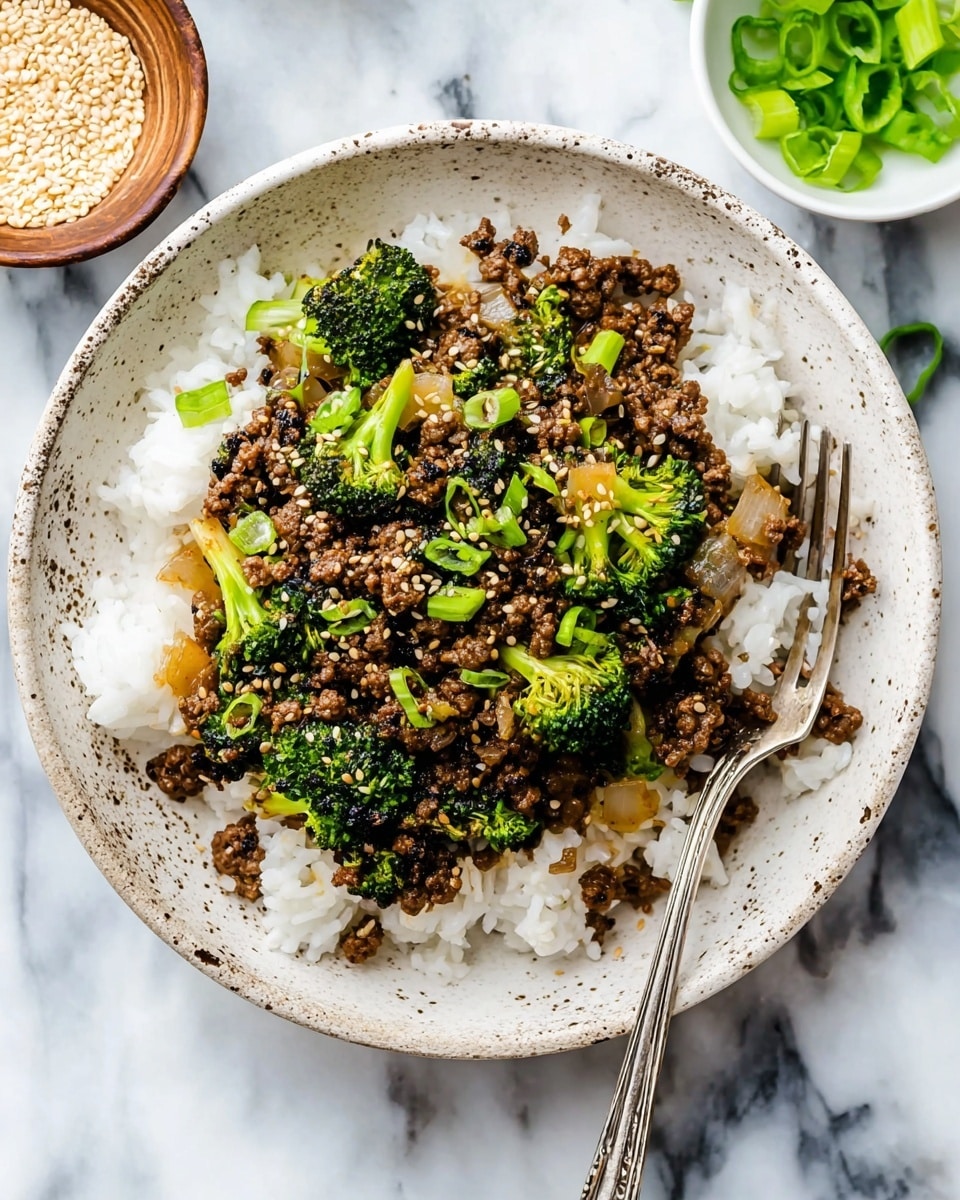 The dish shows a white speckled bowl filled with a base layer of white cooked rice, topped with a mix of dark brown ground meat, bright green broccoli florets, and light brown cooked onion pieces. The meat and vegetables are mixed with small white sesame seeds and thin slices of green onions scattered on top. A silver fork is placed on the right side of the bowl, resting partly on the rice and mixture. The bowl is set on a white marbled surface with a small round bowl of sesame seeds and another container with chopped green onions nearby. photo taken with an iphone --ar 4:5 --v 7