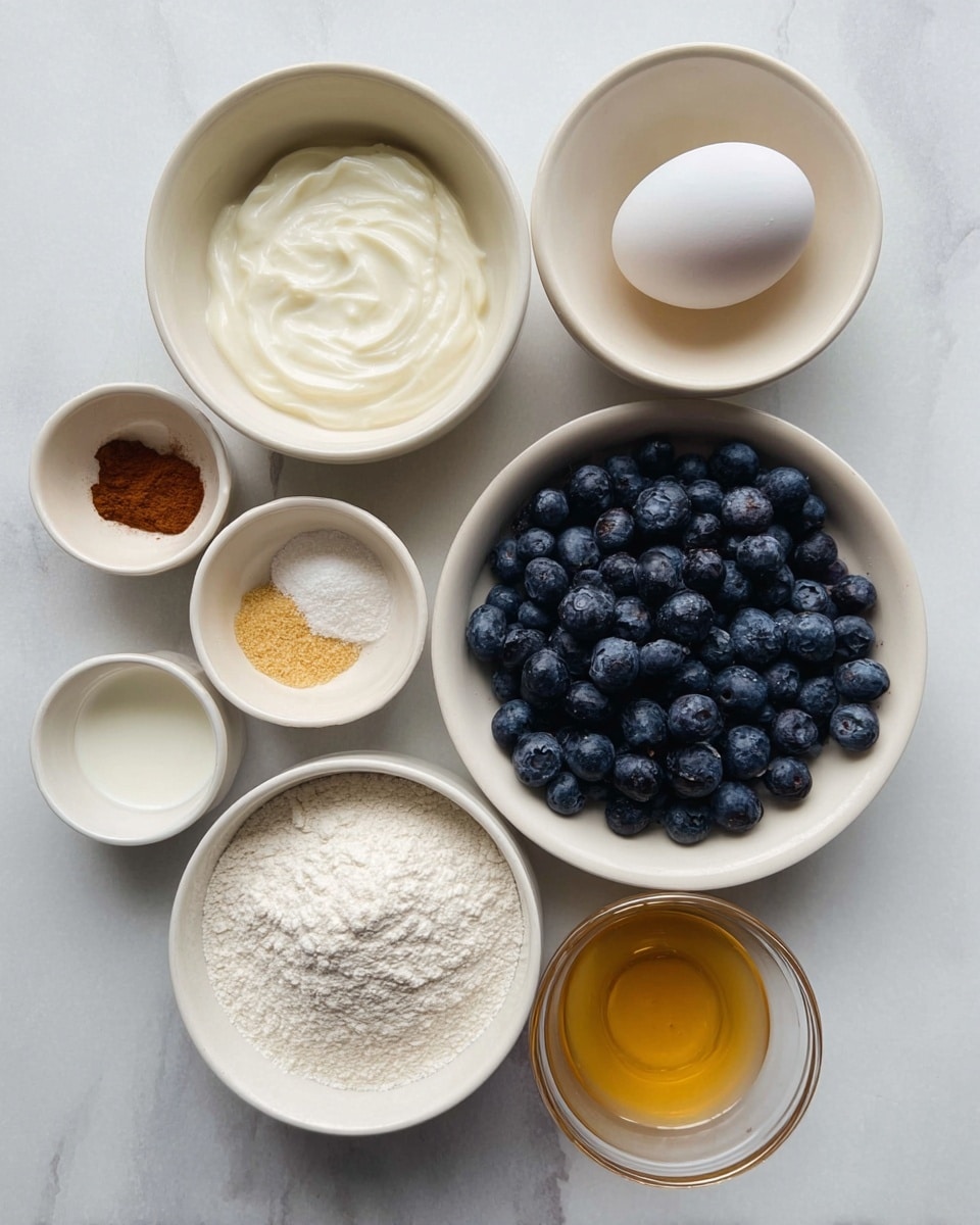 The image shows eight small white bowls arranged on a white marbled surface, each holding a different baking ingredient. Starting from the top and moving clockwise, there is a bowl with creamy yogurt, a bowl with a single white egg, a bowl filled with fresh dark blue blueberries, a bowl containing white flour, a small bowl with white powder mixed with cinnamon, a small bowl with golden liquid, a small transparent bowl with milk, and a bowl with fine yellowish powder. The bowls vary in size, with the largest holding the blueberries at the center right, and all are placed neatly to show the different textures and colors of the ingredients. photo taken with an iphone --ar 4:5 --v 7