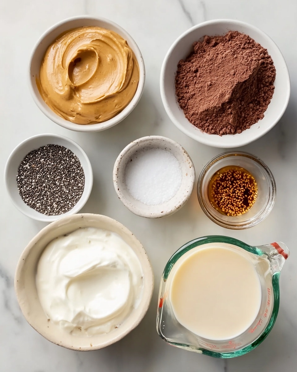 Several small white bowls and a glass measuring cup are arranged on a white marbled surface. The bowls hold different ingredients: one has creamy peanut butter with a smooth texture, another is filled with dark cocoa powder that looks soft and powdery, one contains tiny black chia seeds with a rough texture, and another has thick white yogurt with a creamy surface. There is a bowl with dark maple syrup and a small bowl filled with white salt. The measuring cup contains a pale cream liquid and has a clear glass texture. Photo taken with an iphone --ar 4:5 --v 7