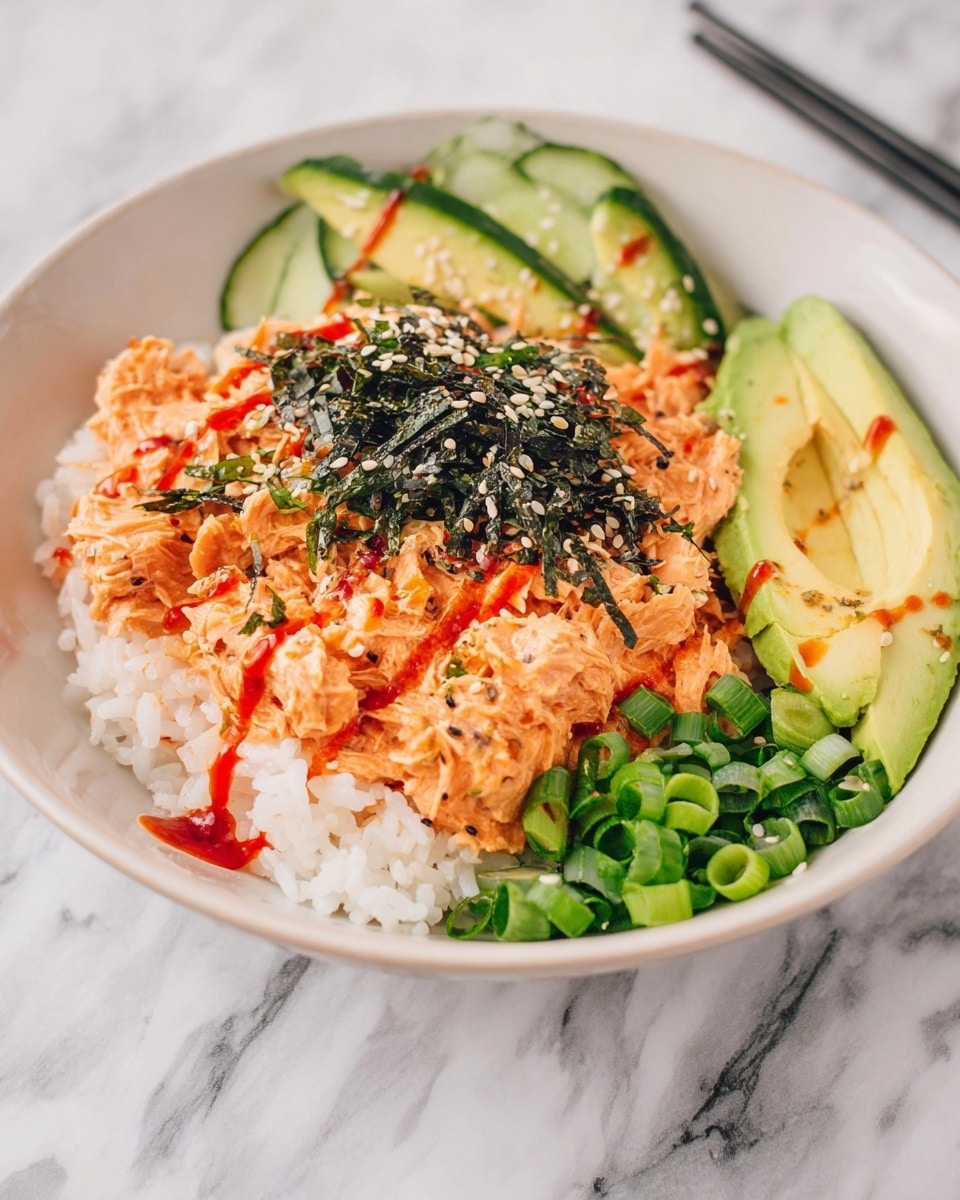 The dish is served in a white bowl on a white marbled surface. It has one base layer of soft white rice with a slightly sticky texture. On top, there are layers of creamy orange shredded salmon mixed with some sauce, dressed with thin lines of red sauce drizzled over it. To the side, there is a fan of light green sliced avocado, a chunk of green cucumber, and a small pile of bright green chopped scallions. The center is sprinkled with black seaweed flakes and white sesame seeds, adding texture and color contrast. photo taken with an iphone --ar 4:5 --v 7