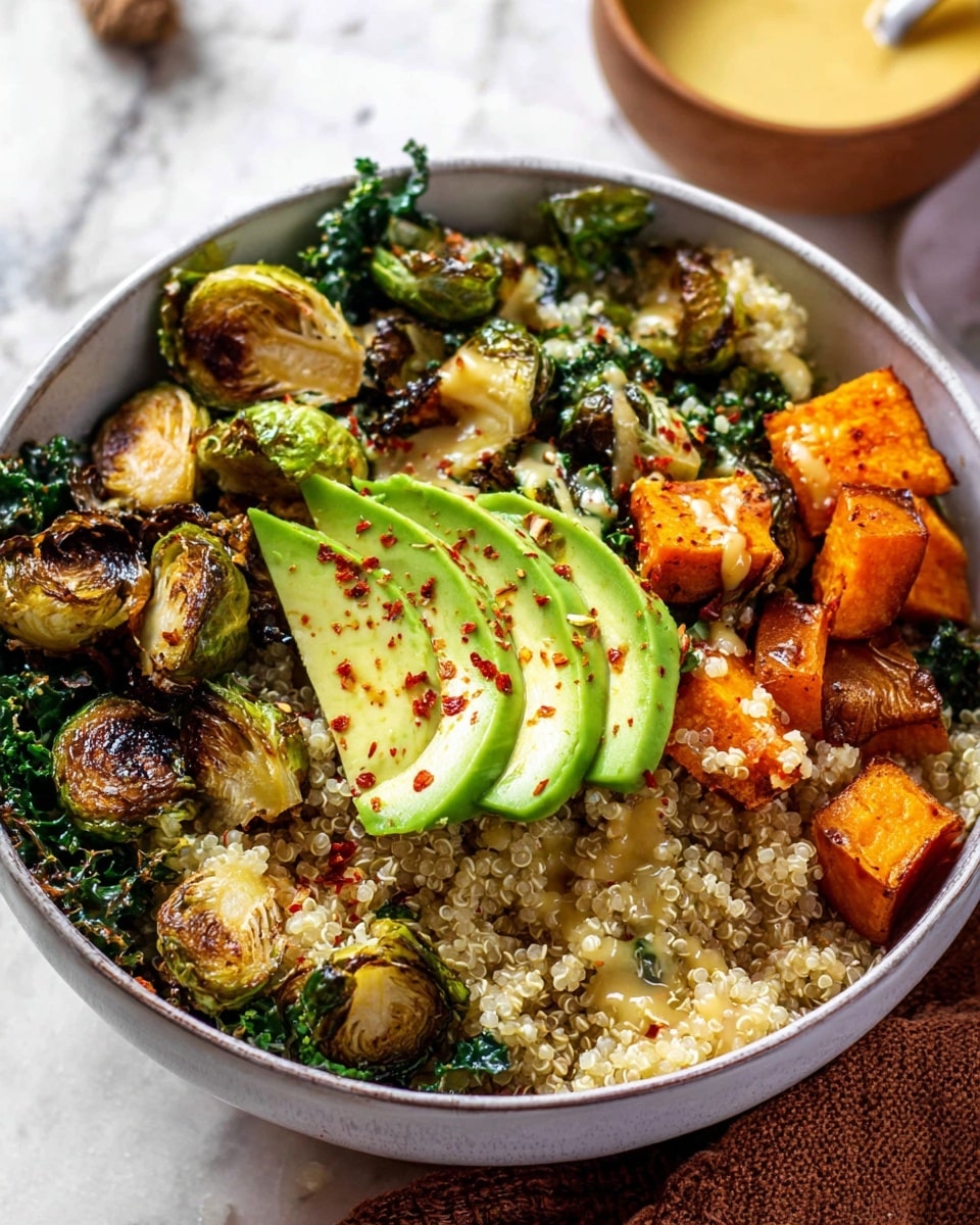 A white bowl filled with cooked quinoa as the base layer, showing a light, fluffy texture with tiny grains. On top, there are dark green kale leaves with a curly texture scattered around. Roasted Brussels sprouts with golden brown charred spots are mixed in, creating a caramelized look. Cubes of roasted sweet potatoes with a bright orange color and crispy edges sit on one side. On top of the bowl, there are two fan-like slices of green avocado sprinkled with red pepper flakes, adding a fresh and creamy contrast. The bowl sits on a white marbled surface with a blurred brown cloth nearby and a small bowl of yellow sauce in the background. Photo taken with an iphone --ar 4:5 --v 7