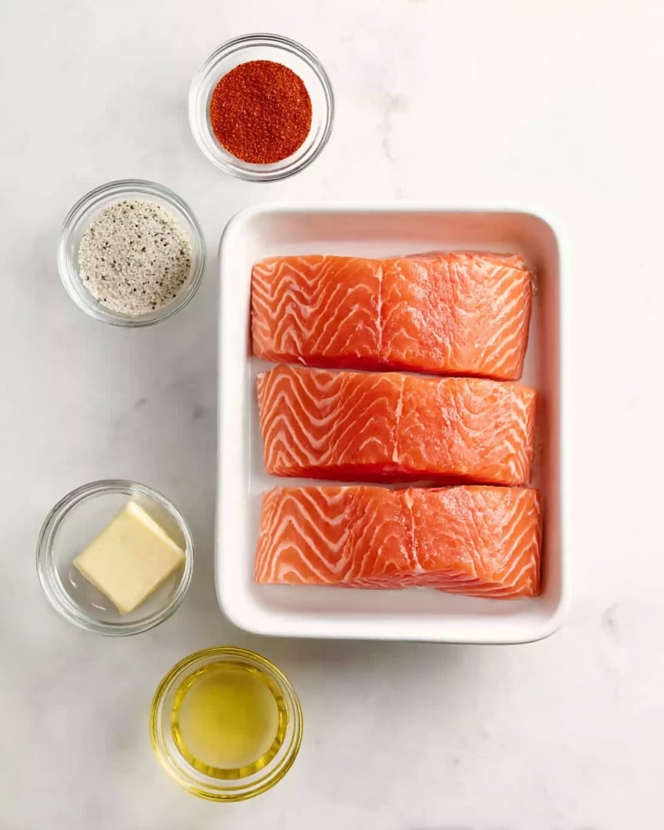 The image shows three raw salmon fillets with a bright orange-pink color and white lines of fat, placed in a white rectangular tray at the center. Surrounding the tray are five small clear glass bowls arranged neatly: to the top is a bowl with light-colored granulated seasoning, to the top left is a bowl with bright red powder, to the bottom left is a bowl with black pepper, to the bottom right is a bowl with pale yellow melted butter, and to the bottom center is a bowl with light yellow oil. All are set on a white marbled surface. The scene is bright and clean. photo taken with an iphone --ar 4:5 --v 7