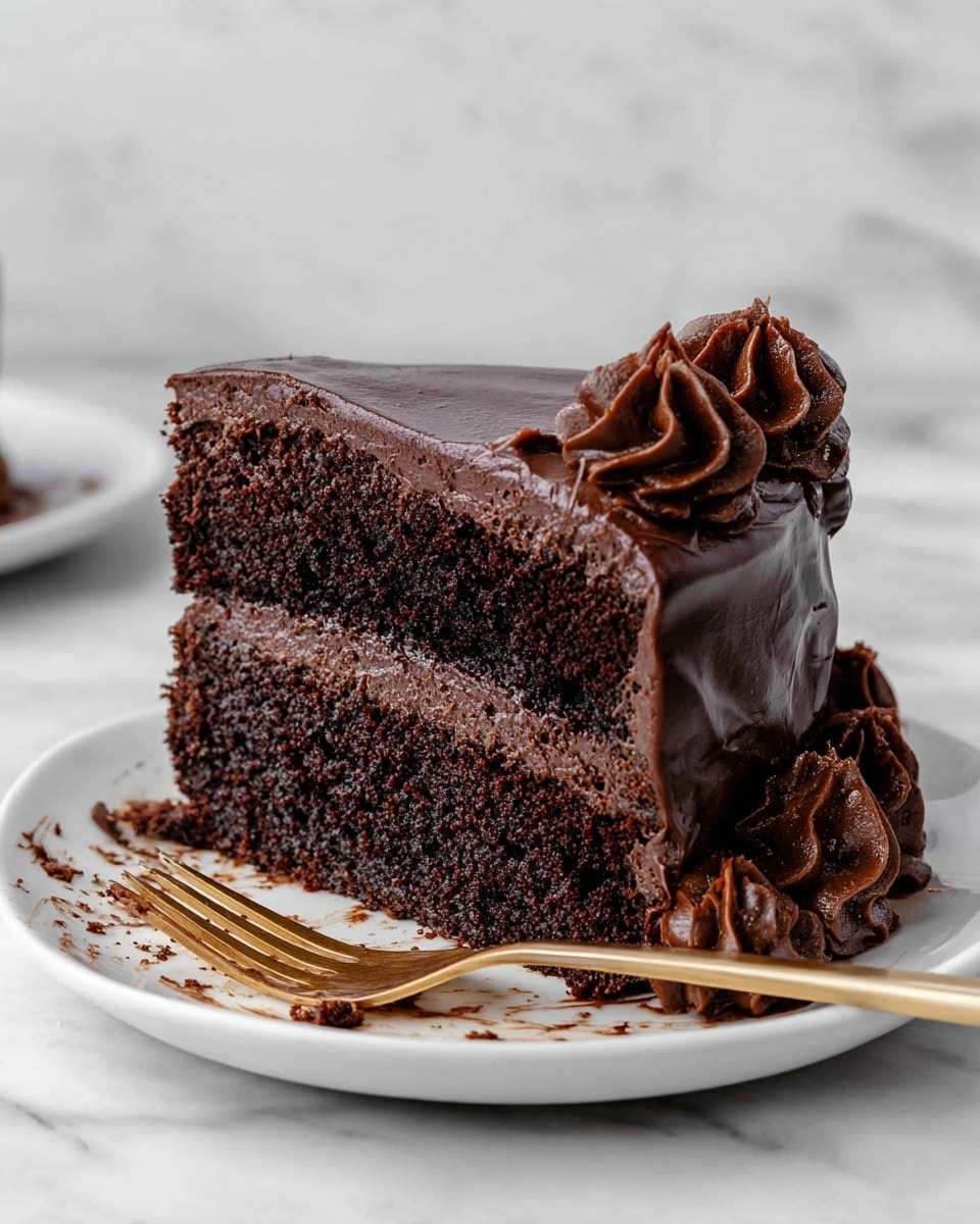 A slice of dark chocolate cake with two thick layers, each layer has rich, moist chocolate sponge cake separated by smooth, thick chocolate frosting. The top is covered with thick glossy chocolate icing that flows down the sides. On the side, there are three swirled dollops of dark chocolate frosting. The slice is on a white plate with chocolate crumbs and smudges, and a golden fork lies next to the cake. The background is a white marbled texture. photo taken with an iphone --ar 4:5 --v 7