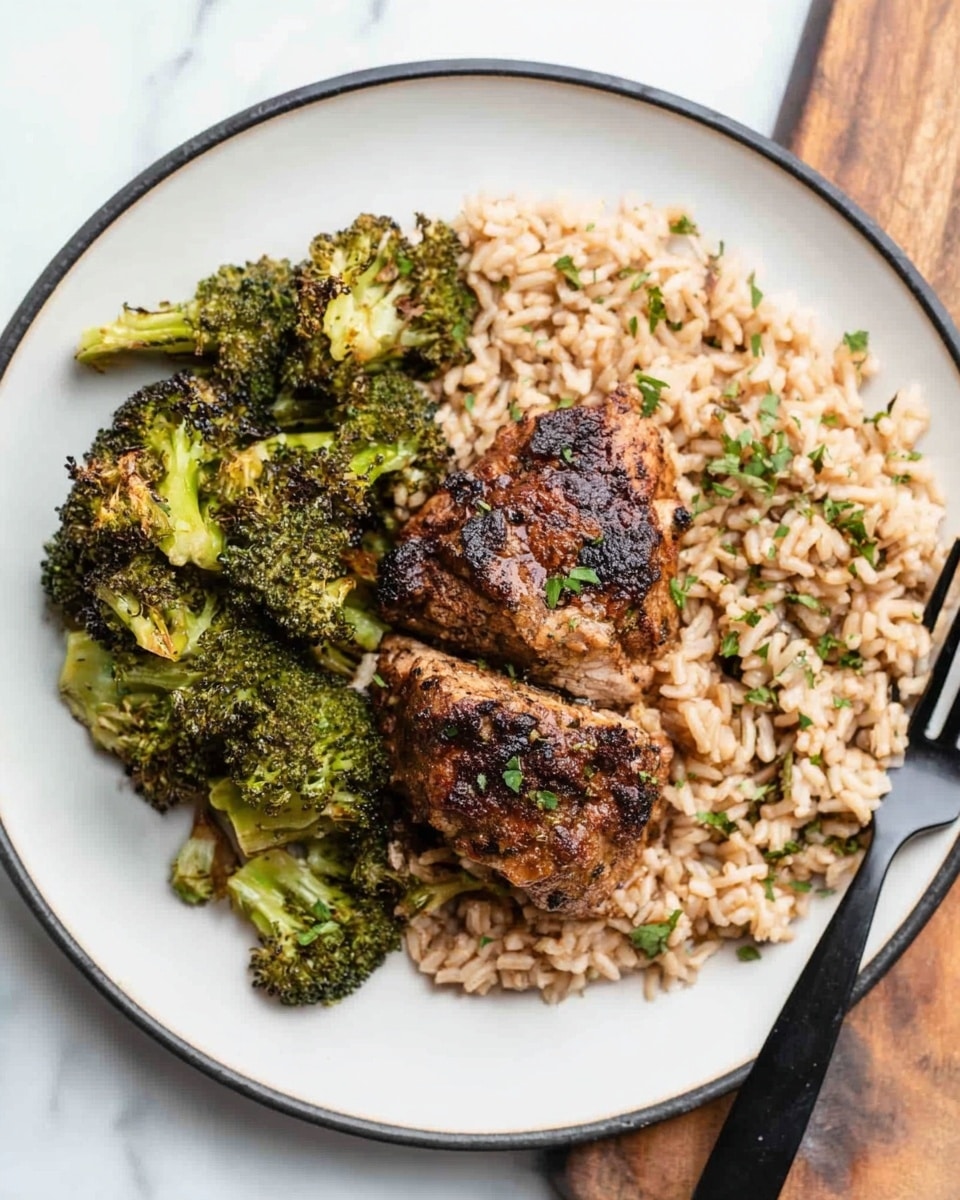 The dish is served on a round white plate with a thin black rim. On the right side of the plate, there is a layer of brown rice that looks soft and mixed with small green herb pieces. On top of the rice, near the center of the plate, two pieces of well-seasoned, browned meat with a slightly crispy texture are placed one on top of the other. On the left side of the plate, there is a pile of roasted broccoli florets, with some edges showing light charring and vibrant green color. The plate is on a white marbled surface, and to the right of the plate, a black fork is visible. Photo taken with an iphone --ar 4:5 --v 7