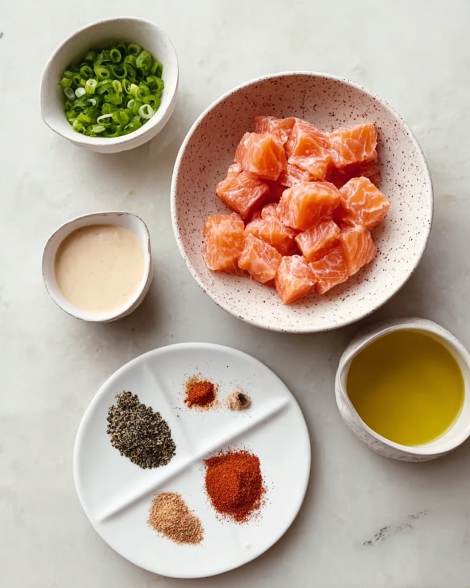 The image shows a white bowl with brown speckles filled with pinkish-orange chunks of raw fish arranged in the center. Above, there is a small white bowl with finely sliced green onions, and beside it a small white cup filled with a pale creamy sauce. Below, there is a white plate divided into sections holding red, black, and brown spices on one side and a light brown spice on the other. To the right of the plate is a white container with a yellow liquid, likely oil. All items are placed on a white marbled surface. Photo taken with an iphone --ar 4:5 --v 7