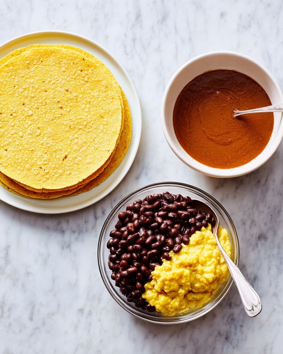 The image shows three main items on a white marbled surface: on the left, a stack of thin, round yellow corn tortillas with a rough texture stacked neatly on a white plate; in the center, a clear glass bowl filled halfway with dark brown beans on one side and mashed yellow chunky substance on the other side, with a silver spoon resting inside; on the right, a white bowl filled with smooth, rich reddish-brown sauce. Photo taken with an iphone --ar 4:5 --v 7