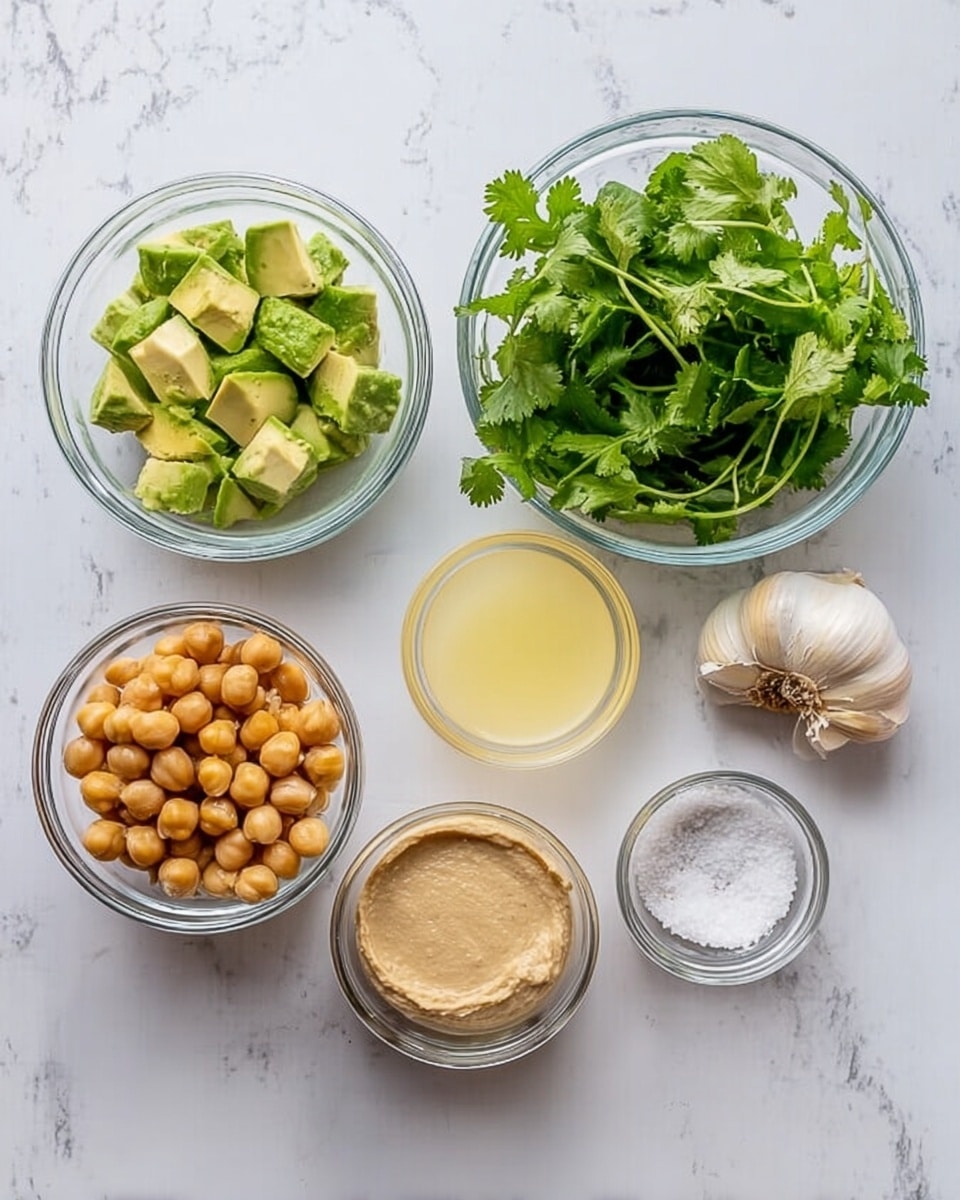 The image shows six clear glass bowls arranged on a white marbled surface. In the top row, from left to right, the first bowl contains light green chopped avocado pieces, the second bowl is filled with fresh green cilantro leaves, and to the right of that, two garlic cloves rest on the marble surface. In the bottom row, from left to right, the first bowl holds round, light brown chickpeas, the second bowl has a light tan creamy spread, the third bowl contains pale yellow lemon juice, and the last bowl holds white granulated salt. The bowls are evenly spaced and the scene is bright and clean, photo taken with an iphone --ar 4:5 --v 7