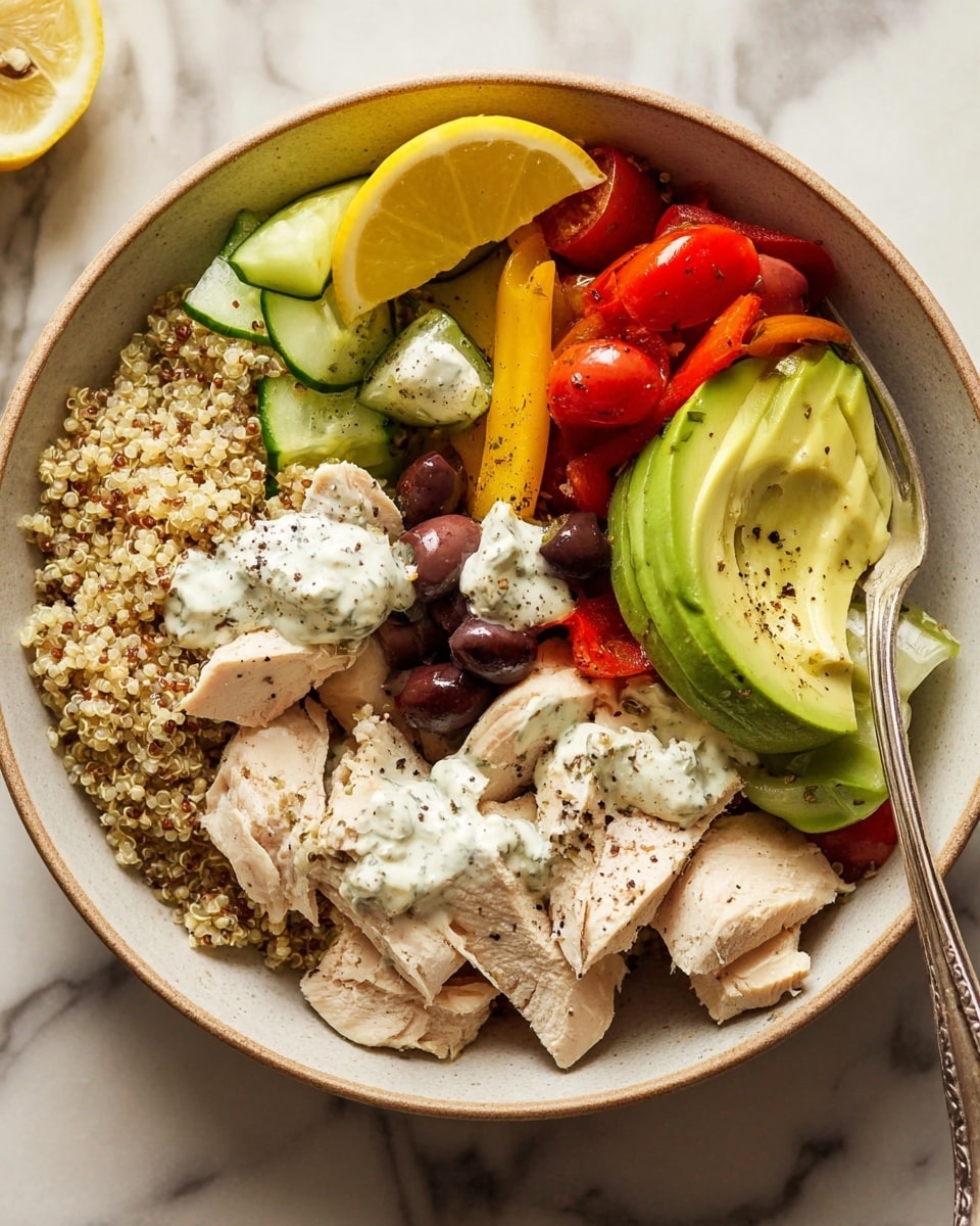A round bowl with a beige rim sits on a white marbled surface, filled with colorful layers of food. The bottom layer is light brown quinoa covering about a third of the bowl's left side. On top, slices of light tan cooked chicken are arranged along the bottom edge. To the right, bright yellow bell pepper strips and pale green cucumber chunks are mixed with small red cherry tomato halves scattered near the top right. In the center, several slices of pale green avocado fan out above the chicken and quinoa. Dollops of creamy white sauce with specks of black pepper are placed at the center and top left, near green and black olives. A wedge of yellow lemon rests on the left edge, adding a fresh touch. A silver spoon is partially visible on the right edge inside the bowl. photo taken with an iphone --ar 4:5 --v 7