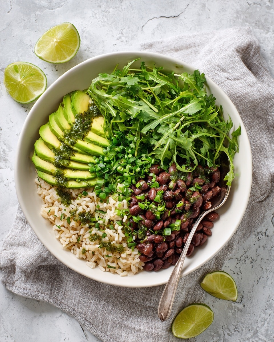 A white bowl contains four main layers arranged side by side. On the bottom left, there is a layer of light brown cooked rice sprinkled with chopped green herbs. To the right of the rice, there is a layer of dark brown cooked beans topped with small green onion slices. Above the rice, bright green avocado slices are fanned out and topped with a drizzle of green herb sauce. Next to the avocado, a mixture of leafy greens including cilantro and arugula creates a fresh, textured layer with a few lime wedges placed on top. A silver spoon rests inside the bowl on the right edge. The bowl sits on a white marbled surface with a light gray cloth underneath and lime wedges nearby. Photo taken with an iphone --ar 4:5 --v 7