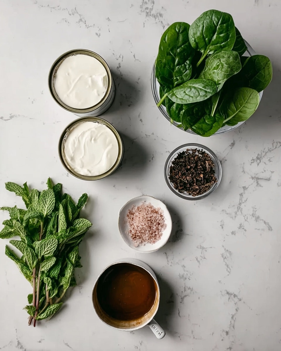 The image shows a flat lay of several ingredients on a white marbled surface. There are two open cans with white cream inside placed toward the top left. Fresh green spinach leaves are at the top right. In the middle right, a clear bowl contains small dark brown bits. Below the spinach and cream, a small heap of pink salt rests on the surface next to a tiny white dish filled with brown liquid. At the bottom left, there is a bundle of fresh green leaves that look like mint. On the bottom right, a white pan filled with dark brown liquid also sits on the marble surface. The ingredients are spaced apart with no overlapping. photo taken with an iphone --ar 4:5 --v 7