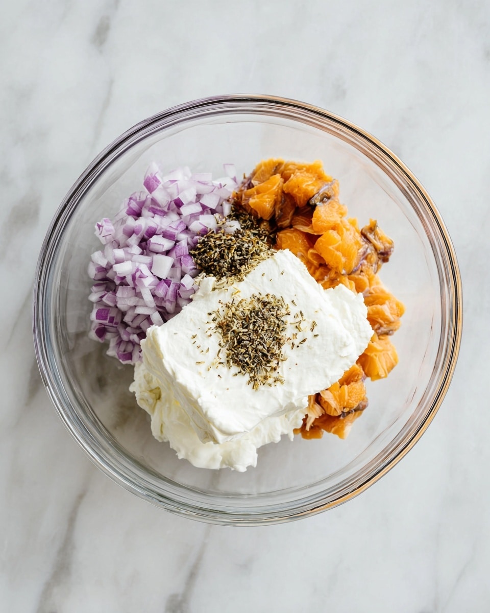 A clear glass bowl is placed on a white marbled surface, filled with three main layers. The bottom layer has a large block of smooth, white cream cheese centered in the bowl, creating a soft texture. To the left of the cream cheese is a mound of finely chopped purple and white onions adding a crunchy texture and light pastel color. To the right side of the cream cheese, chunks of cooked orange salmon with dark skin pieces are slightly scattered. On the top of the cream cheese near the salmon, there is a small layer of ground black pepper adding a speckled dark detail. photo taken with an iphone --ar 4:5 --v 7