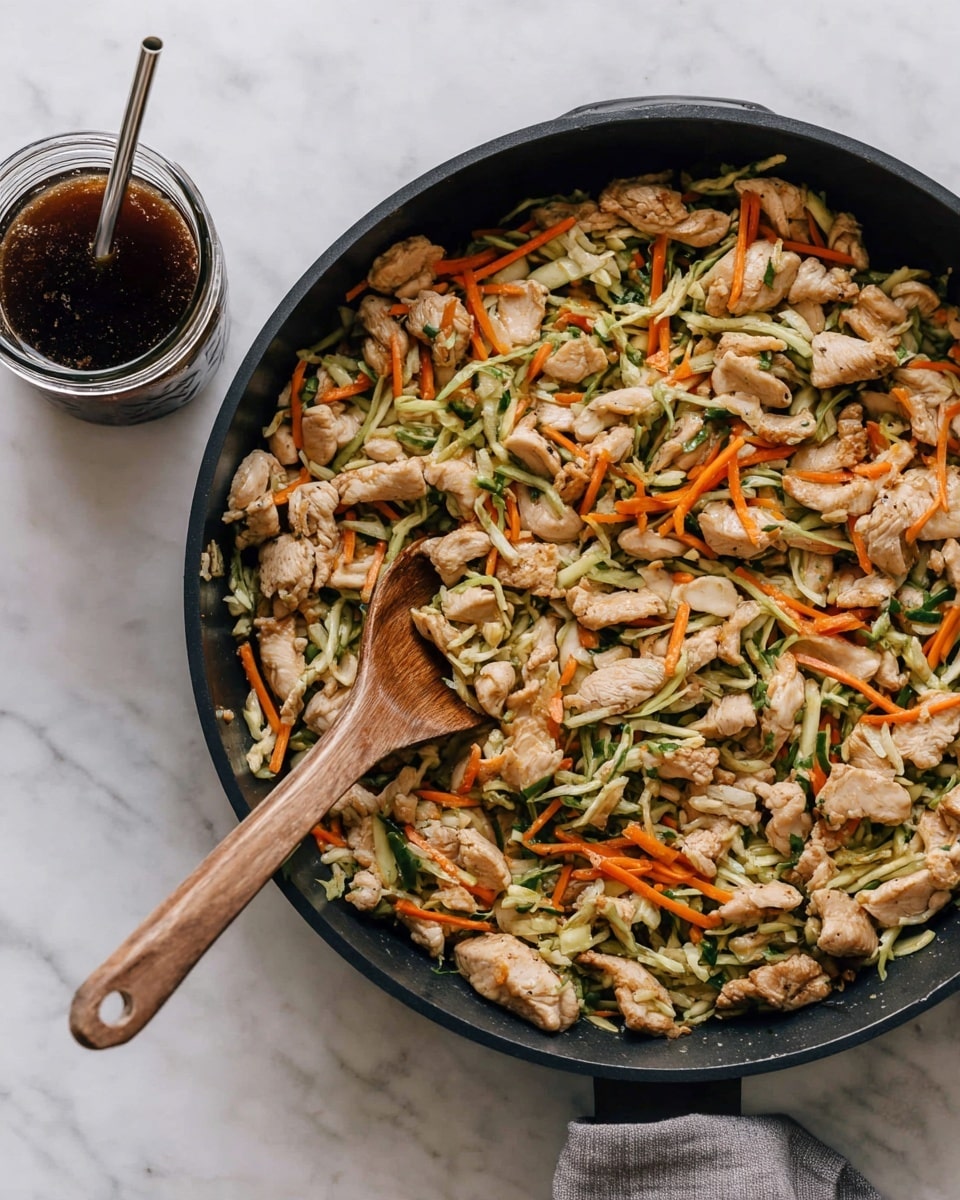 A black pan filled with a mix of light beige cooked chicken pieces, thin strips of green vegetables, and thin orange carrot sticks spread evenly. A light wooden spoon is resting inside the pan, partially buried under the food. Next to the pan, a clear glass jar holds a dark brown liquid with a silver metal straw inside. The background is a white marbled texture. photo taken with an iphone --ar 4:5 --v 7