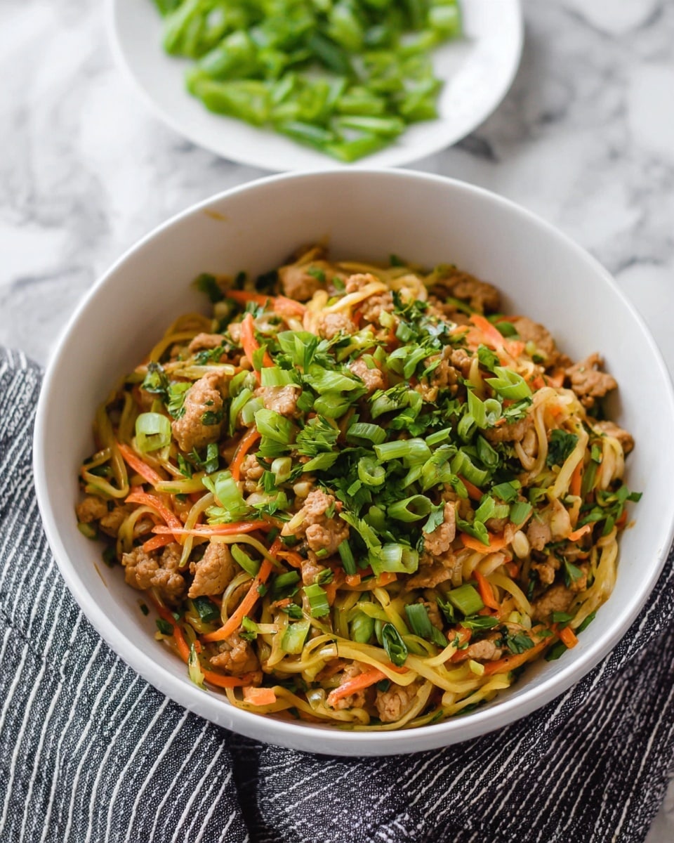 A white bowl filled with a colorful stir-fry dish sits on a white marbled surface with a black and white striped cloth underneath. The dish has three main layers: the bottom layer contains thin, light yellow vegetable strips mixed with thin orange carrot strips, the middle layer is made of small pieces of light brown cooked meat, and the top layer is garnished with bright green chopped fresh herbs and sliced green onions scattered evenly. In the background, a white plate holds more chopped green onions. The overall look is fresh and vibrant with mixed textures of soft meat and crunchy vegetables photo taken with an iphone --ar 4:5 --v 7