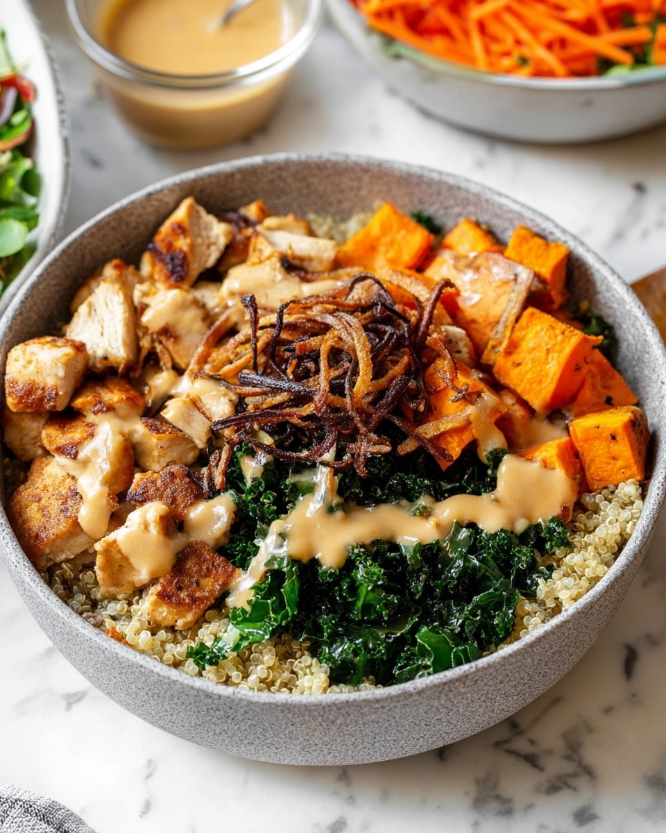 A bowl with five layers is shown on a white marbled surface. The bottom layer fills the bowl with small, light tan quinoa grains. On the top left, there are medium-sized, cubed, lightly browned chicken pieces with a slightly charred texture. Beside the chicken, on the top right, chunks of bright orange roasted sweet potatoes with skins are placed. Below the sweet potatoes, dark green chopped kale mixed with thin strips of orange carrot lies fresh. On top of the center, a crown of thin, crunchy, dark brown fried onions is layered over a drizzle of creamy beige sauce that is spread lightly across the middle of the bowl. In the background, a partial view of a bowl with green salad and orange carrot strips, and a small glass bowl of light brown dressing, are also visible. photo taken with an iphone --ar 4:5 --v 7