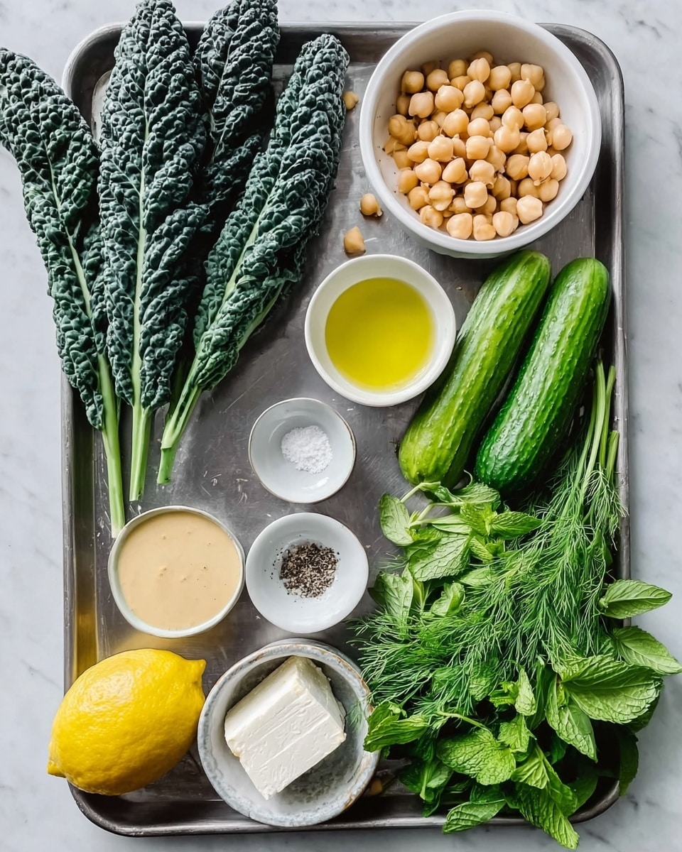 The image shows a silver tray with various fresh ingredients neatly arranged on a white marbled surface. On the left side are three long black kale leaves with textured, curly edges. Next to them are three small green cucumbers placed horizontally. In the top right corner, there is a white bowl filled with light brown chickpeas. Below the chickpeas, a small white bowl holds a golden liquid that looks like olive oil. A whole yellow lemon is near the center of the tray. To the left of the lemon are two small white bowls, one with a light beige creamy sauce, and the other with a pale yellow liquid. Below these, there is a small white dish with salt and black pepper. At the bottom center of the tray, a white bowl contains a soft white block of cheese. On the bottom right, bunches of fresh green herbs like dill, parsley, and mint add color and texture. The scene is bright and clean with natural lighting, photo taken with an iphone --ar 4:5 --v 7