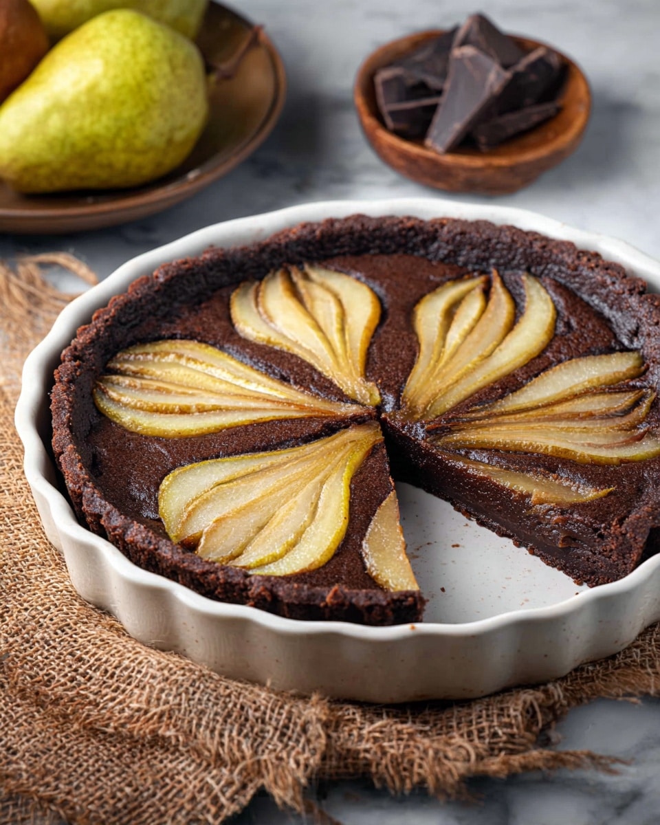 A round chocolate tart in a white ceramic dish with a dark brown, rich-looking crust and filling. On top, there are four fan-shaped pear slices, each golden yellow with a slightly shiny texture, evenly placed around the tart. One wedge of the tart is cut and pulled slightly out, showing the dense chocolate layer beneath the pears. The tart sits on a piece of coarse burlap fabric, and blurred in the background are two whole pears and a small wooden bowl with dark chocolate chunks. The surface under everything is white marbled texture. photo taken with an iphone --ar 4:5 --v 7