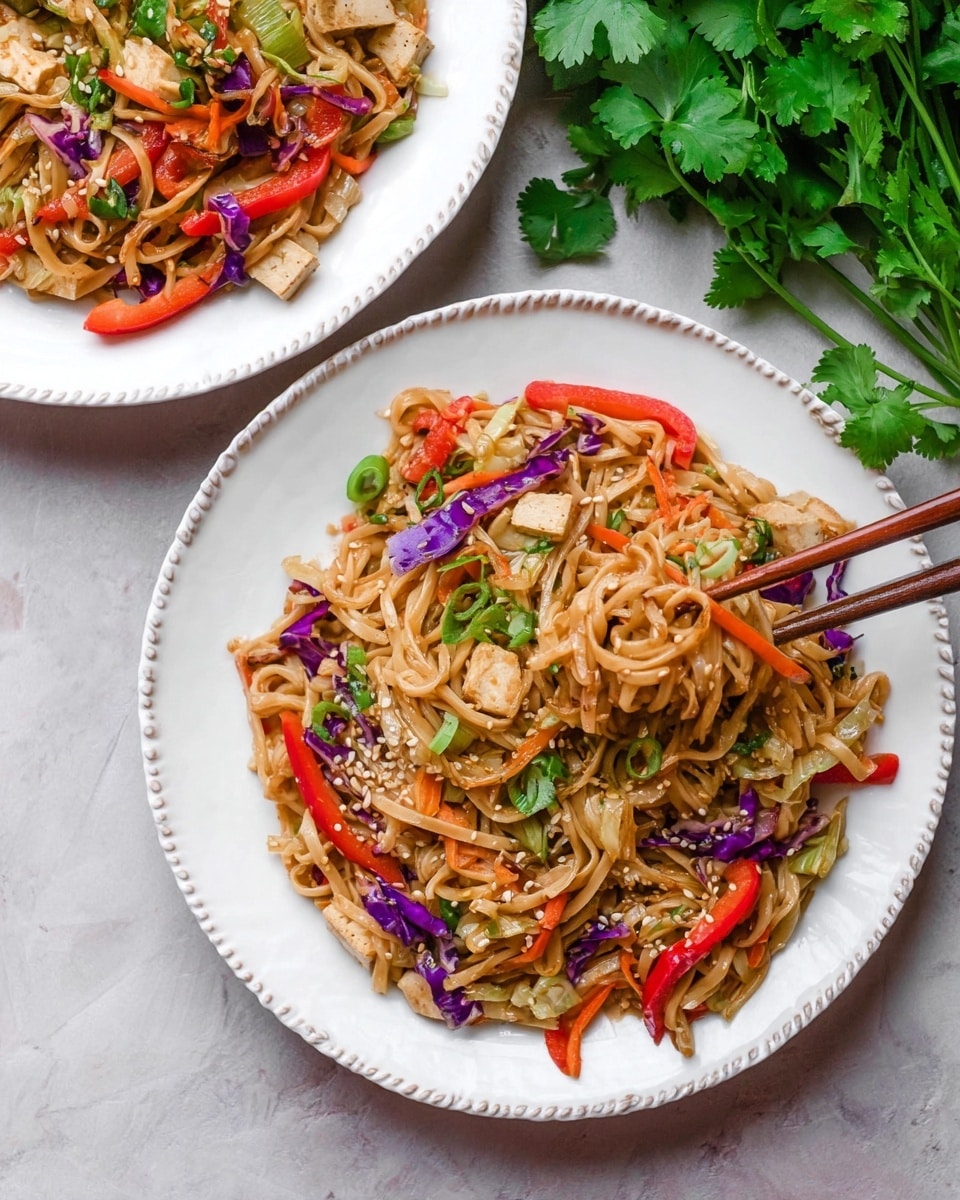 The image shows two white plates with a rope-like edge filled with stir-fried noodles mixed with colorful vegetables and tofu. The noodles are light brown and form the base layer, with thin strips of red bell pepper, bright purple cabbage, and green herbs scattered throughout. Small beige tofu pieces are mixed evenly among the noodles and vegetables. The dish is garnished with chopped green onions and sesame seeds. One plate is partly visible at the top, while the plate in the foreground has a pair of wooden chopsticks lifting some noodles. The plates rest on a white marbled surface, with fresh green cilantro leaves placed nearby. Photo taken with an iphone --ar 4:5 --v 7